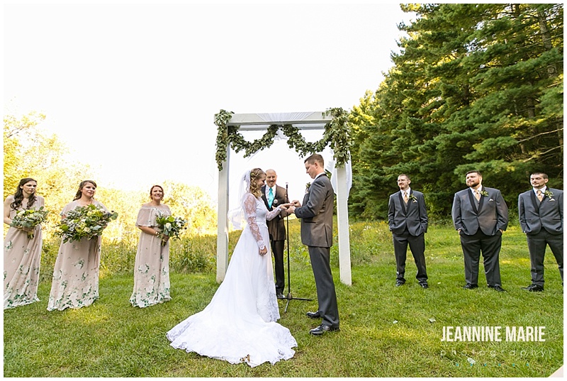 ring exchange, outdoor wedding, floral arch, wedding party, bride, groom, rings, wedding rings, The Round Barn, Jeannine Marie Photography, Minnesota wedding photographer, Saint Paul wedding photographer, barn wedding, farm wedding, rustic wedding, Minnesota barn wedding, Minnesota farm wedding, vintage wedding gown, vintage wedding, Heather Rosales, Artemisia Studios, A'Britin Catering, Valley Pastries, Midwest Sound, Roadkill, Liana Harding, Katie Brown Studios, JenMar Creations, DSW, ShowMeYourMumu, Savvi Formalwear, Minnesota Coaches, wedding inspiration, Minnesota wedding, Round Barn Farm wedding photographer, outdoor wedding, field wedding, September wedding, Minnesota Bride, Midwest Bride